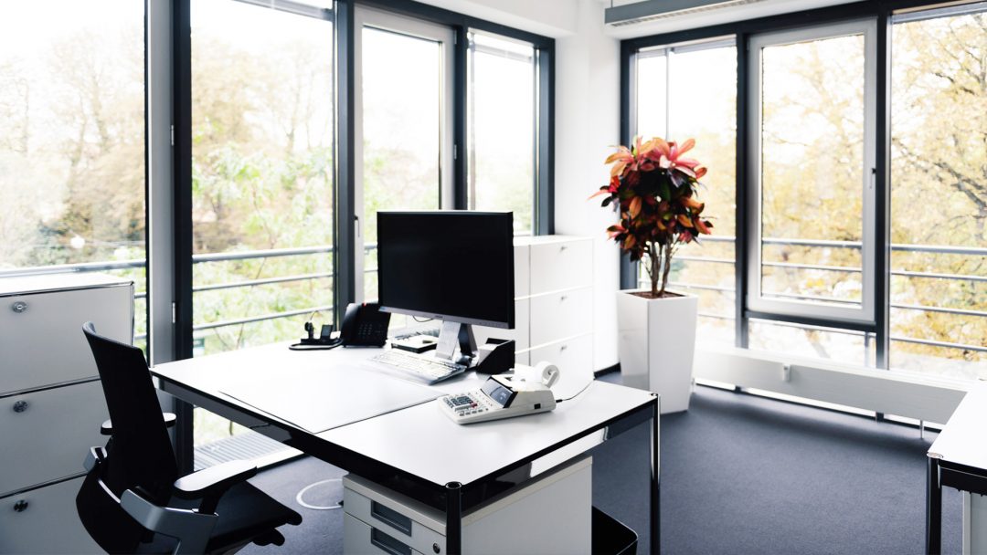 Lichtdurchflutetes, modernes Büro in der Kanzlei mit ergonomischen Möbeln und großen Monitoren.